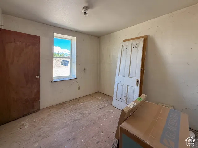 Room featuring a single window, a flush-mount ceiling light, and unfinished flooring