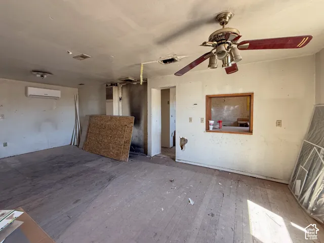 Interior space featuring a pass-through window, overhead lighting, and a wall-mounted air conditioning unit