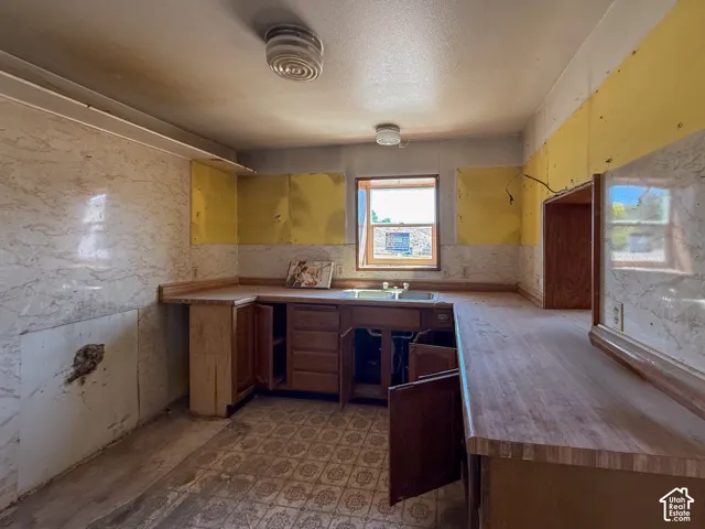 Kitchen featuring wood-finish countertops, base cabinetry, a built-in sink, and a recessed appliance opening
