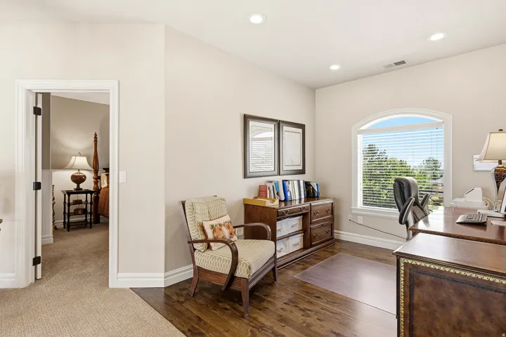 Loft/Flexible Space Overlooking the Great Room with Rich Wood Flooring, an Arched Window, Recessed Lighting, and Crisp White Trimwork