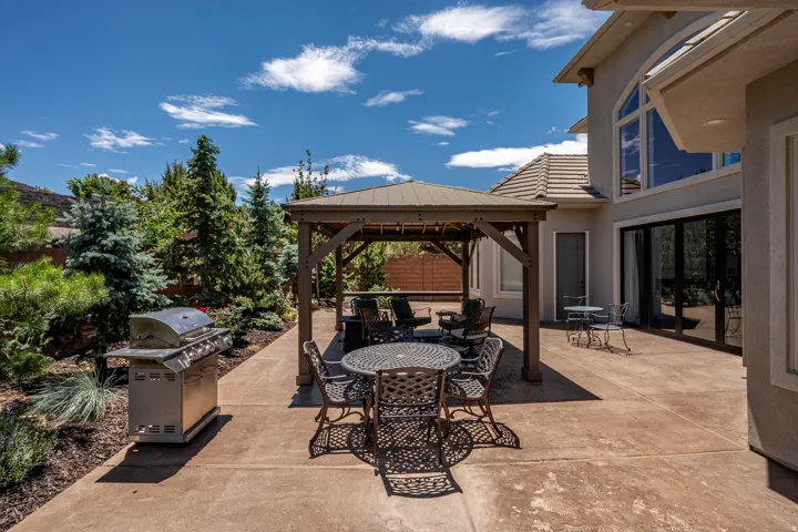 Expansive Stamped Concrete Patio On the Otherside of the Large Stacking Great Room Doors Designed for Outdoor Entertaining Showcasing a Gazebo and Mature Evergreen Landscaping
