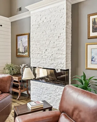 Inviting Fireplace Featuring a Linear Glass-Enclosed Firebox, White Stacked Stone Surround, and Crown Molding