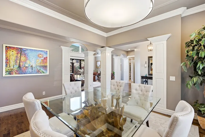 Formal Dining Area Featuring Hardwood Flooring, Extensive Crown Molding, and Architectural Columns Defining the Entryway