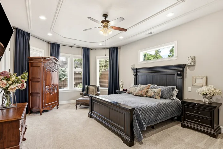 Primary Suite with Abundant Natural Light and Recessed Lighting Illuminates a Tray Ceiling with Decorative Molding and Private Patio Access