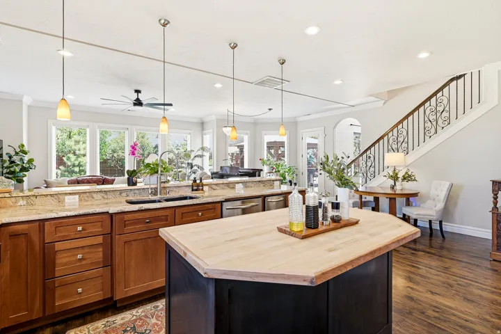 Gourmet Open-Concept Chef's Kitchen Featuring a Wood-Finish Island with a Butcher Block Countertop, Granite Perimeter Countertops, and Stainless Steel Appliances