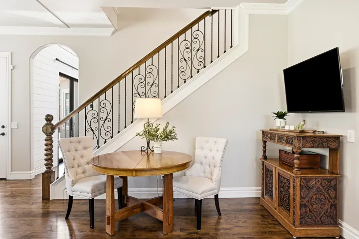 Staircase to the Second Level Featuring Decorative Iron Balusters and a Polished Wood Handrail with Flex Space off the Kitchen and Second Living Room Currently Utilized as a Casual Dining Area