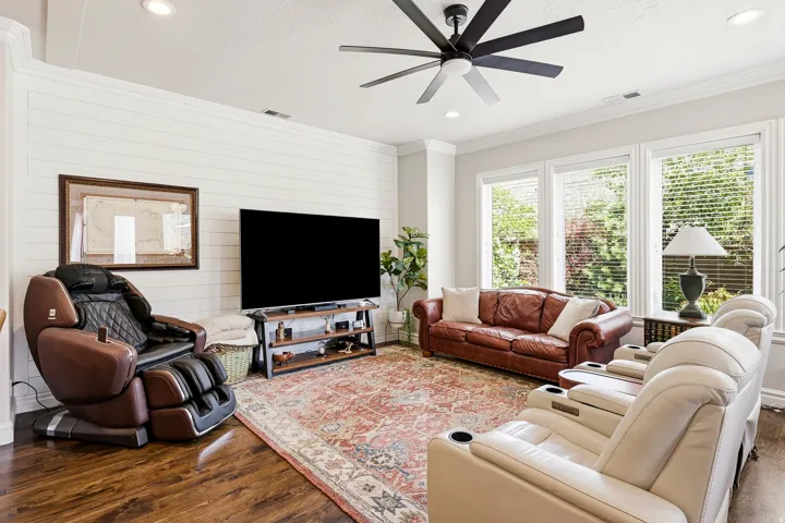 Comfortable Versatile Lower-Level Secondary Living Space with Media and Game Room Potential. Wood Flooring, Recessed Lighting, and a Ceiling Fan with Large Windows and Door Access to the Back Yard