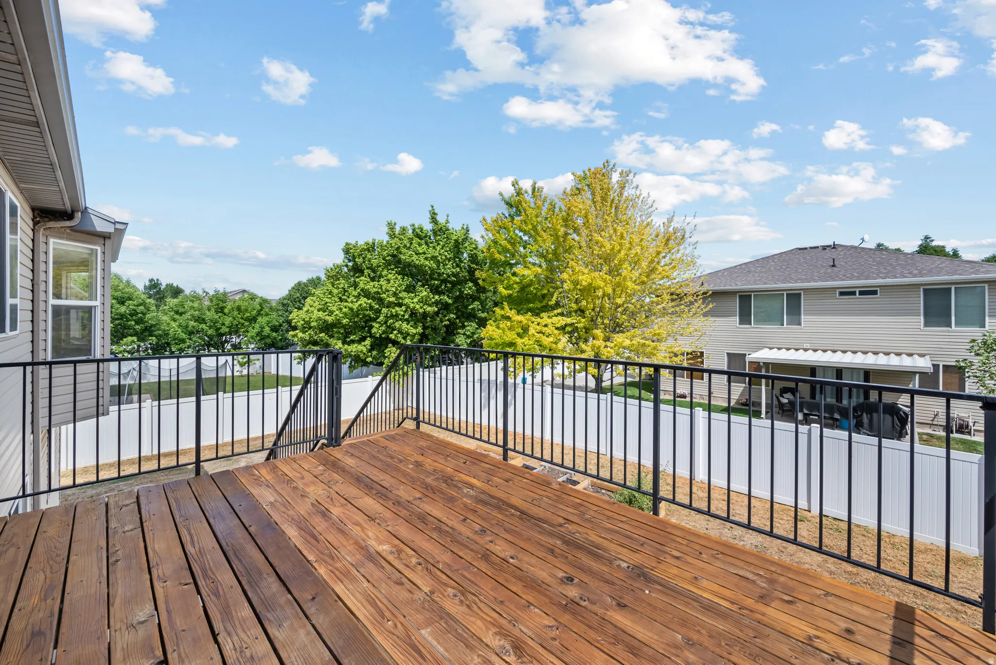 Expansive outdoor deck with rich wood-finish flooring and black metal railings