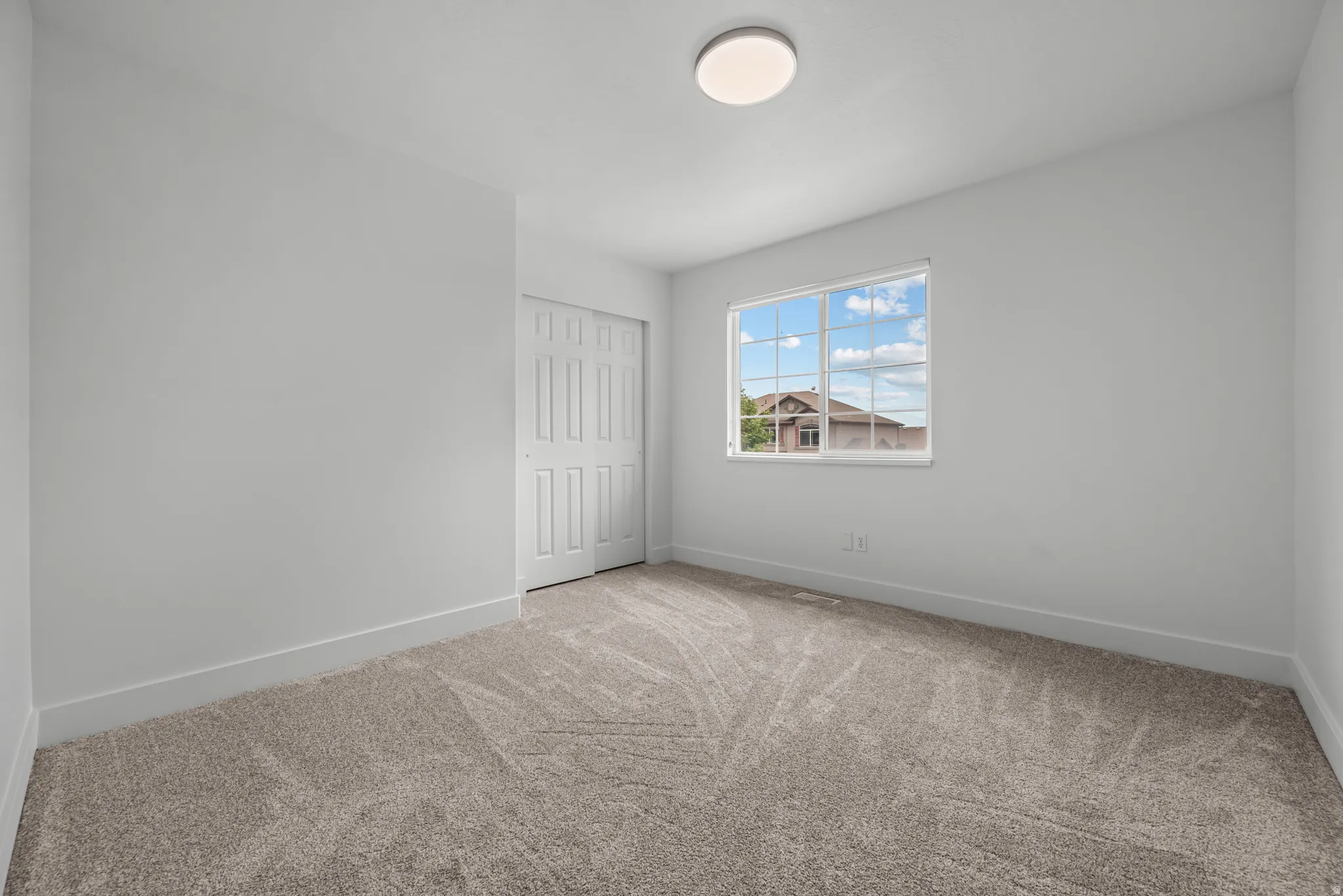 Interior room featuring light gray walls, plush gray patterned carpet, and white baseboards