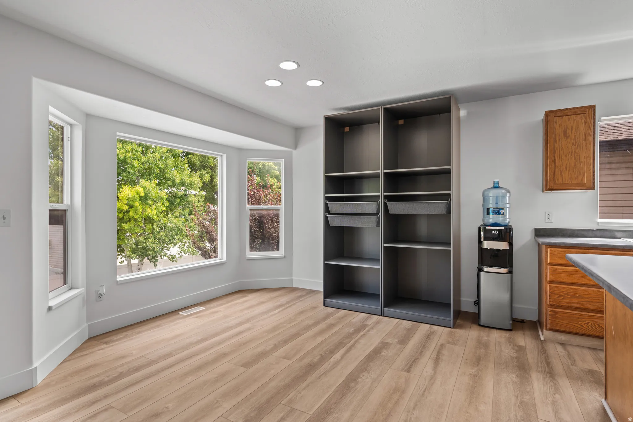 Spacious room featuring wood-finish flooring and a bright bay window