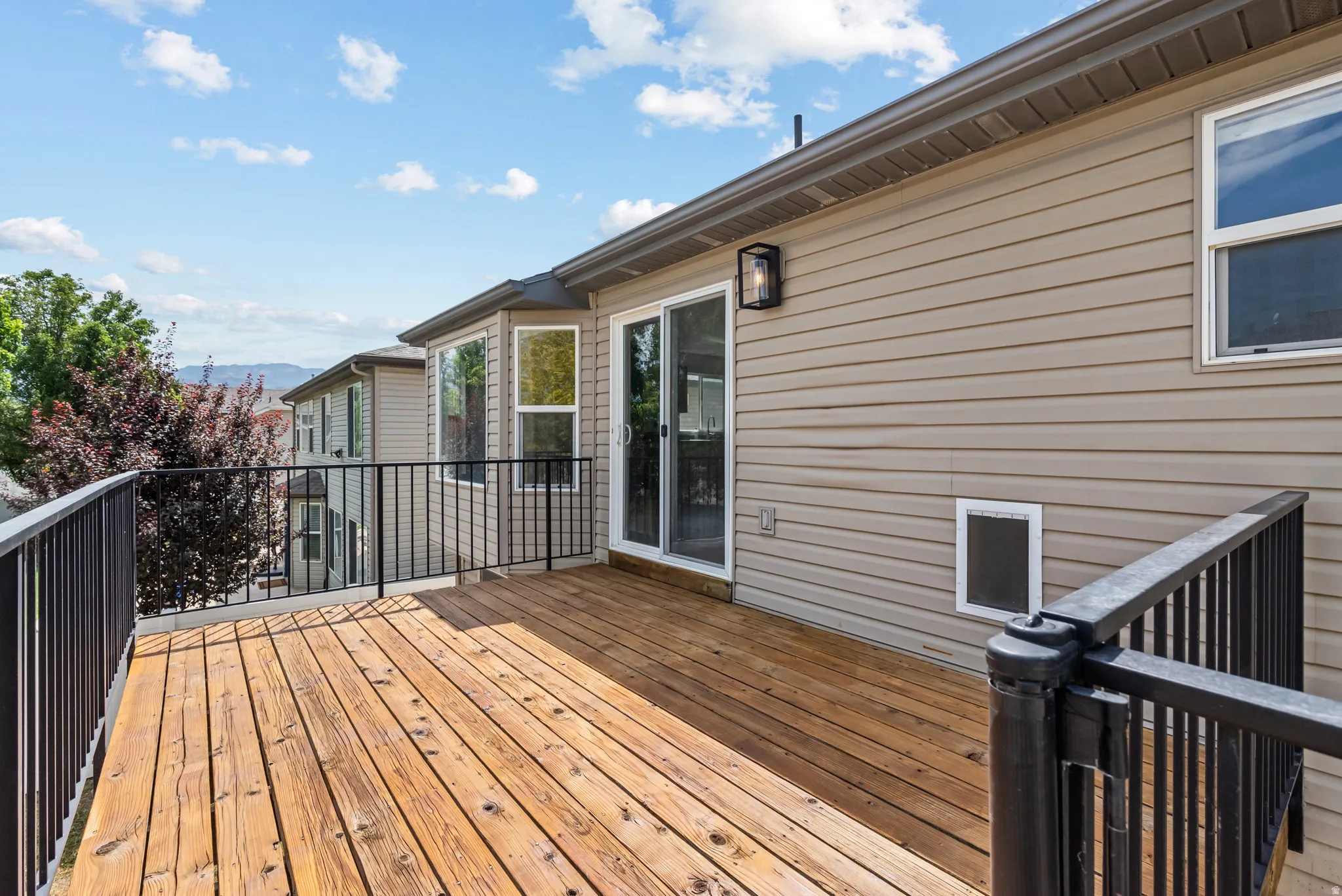 Spacious outdoor deck featuring wood flooring and black metal railing