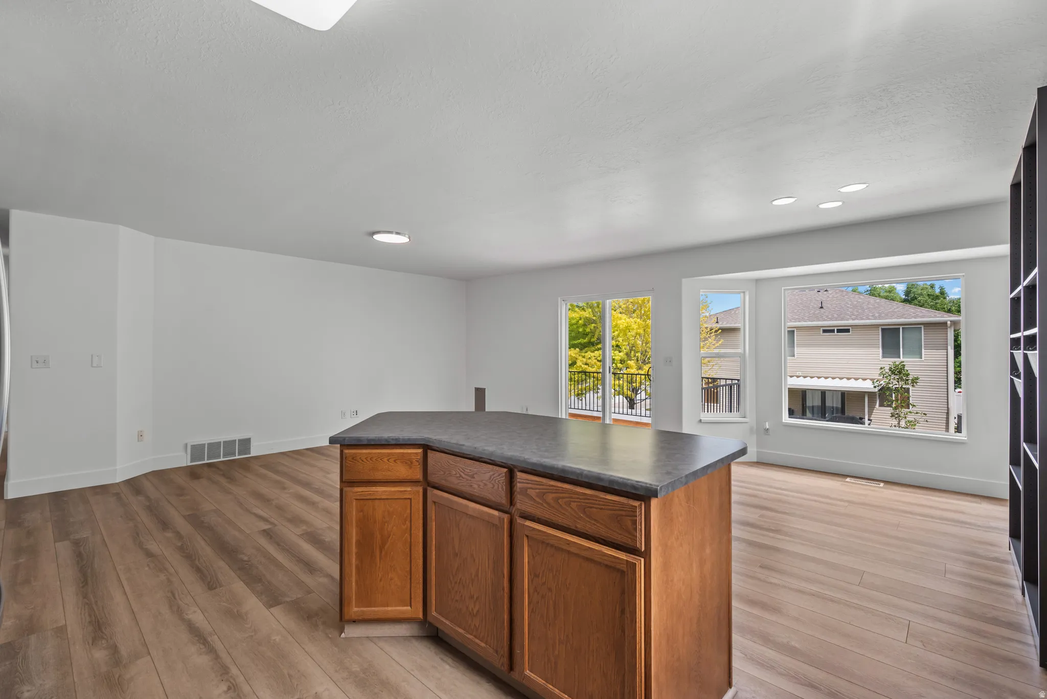 Kitchen island with wood-finish cabinetry and a dark countertop