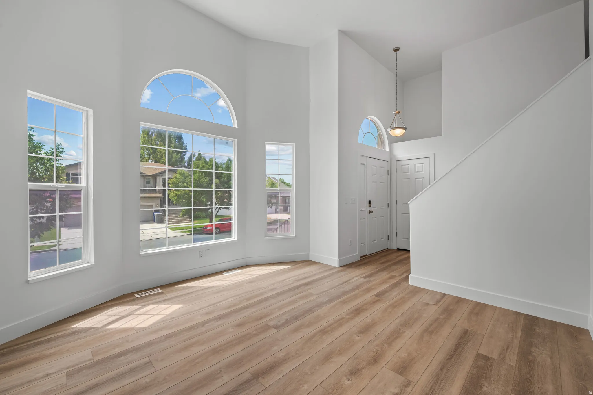 Vaulted ceiling great room with abundant natural light from large windows, including a prominent arched window