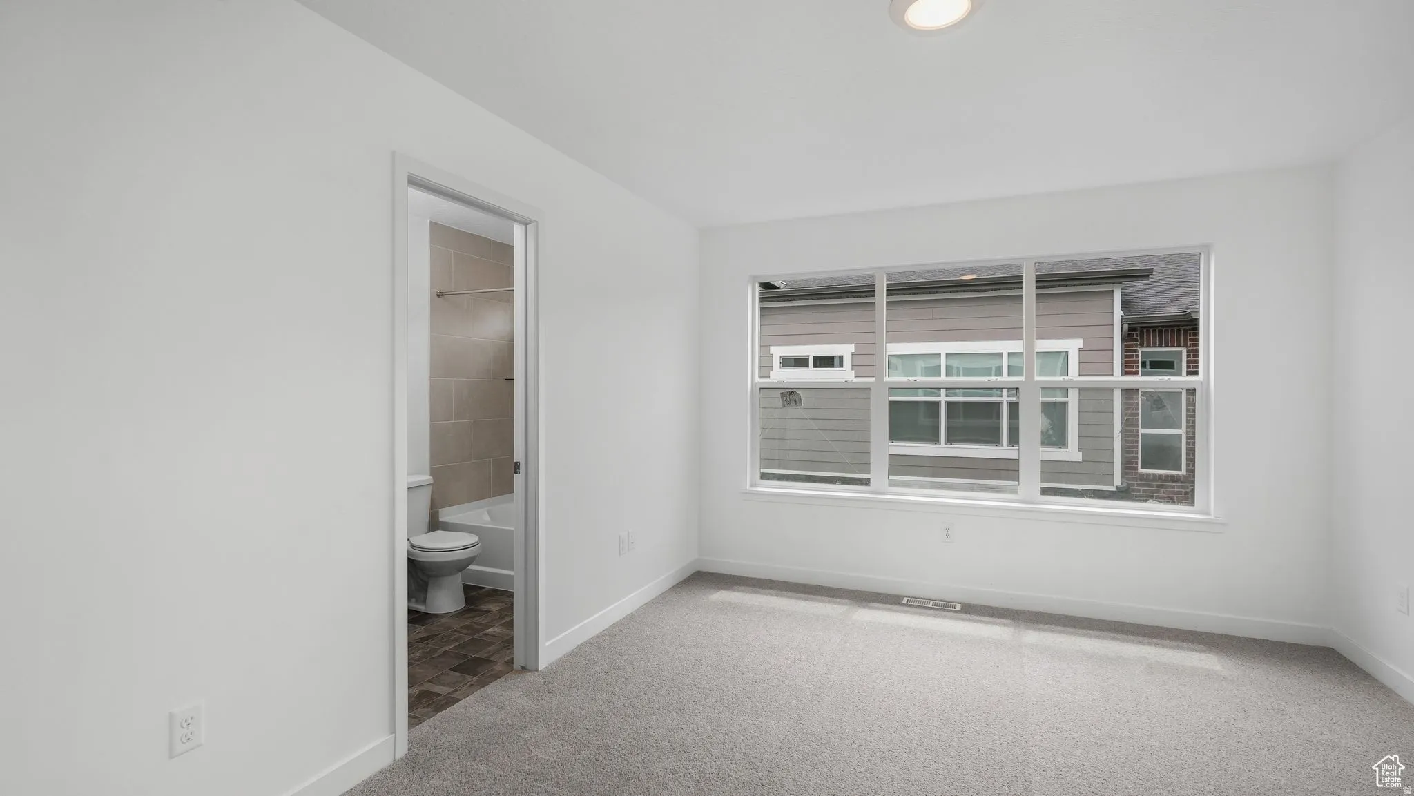 Spacious room featuring light gray carpeting and a large multi-pane window