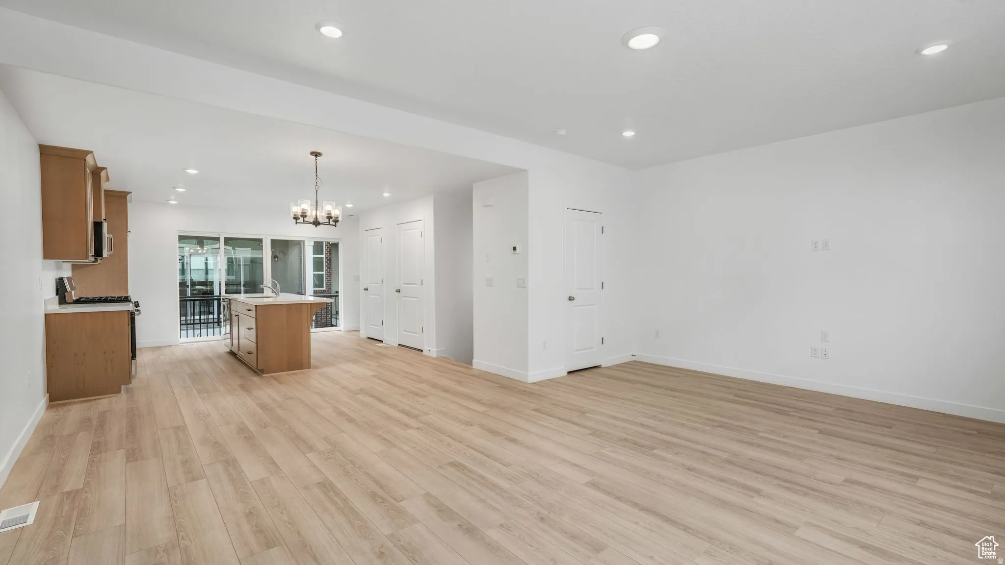Expansive room featuring wood-finish flooring, recessed lighting, and a modern kitchen island with an integrated sink