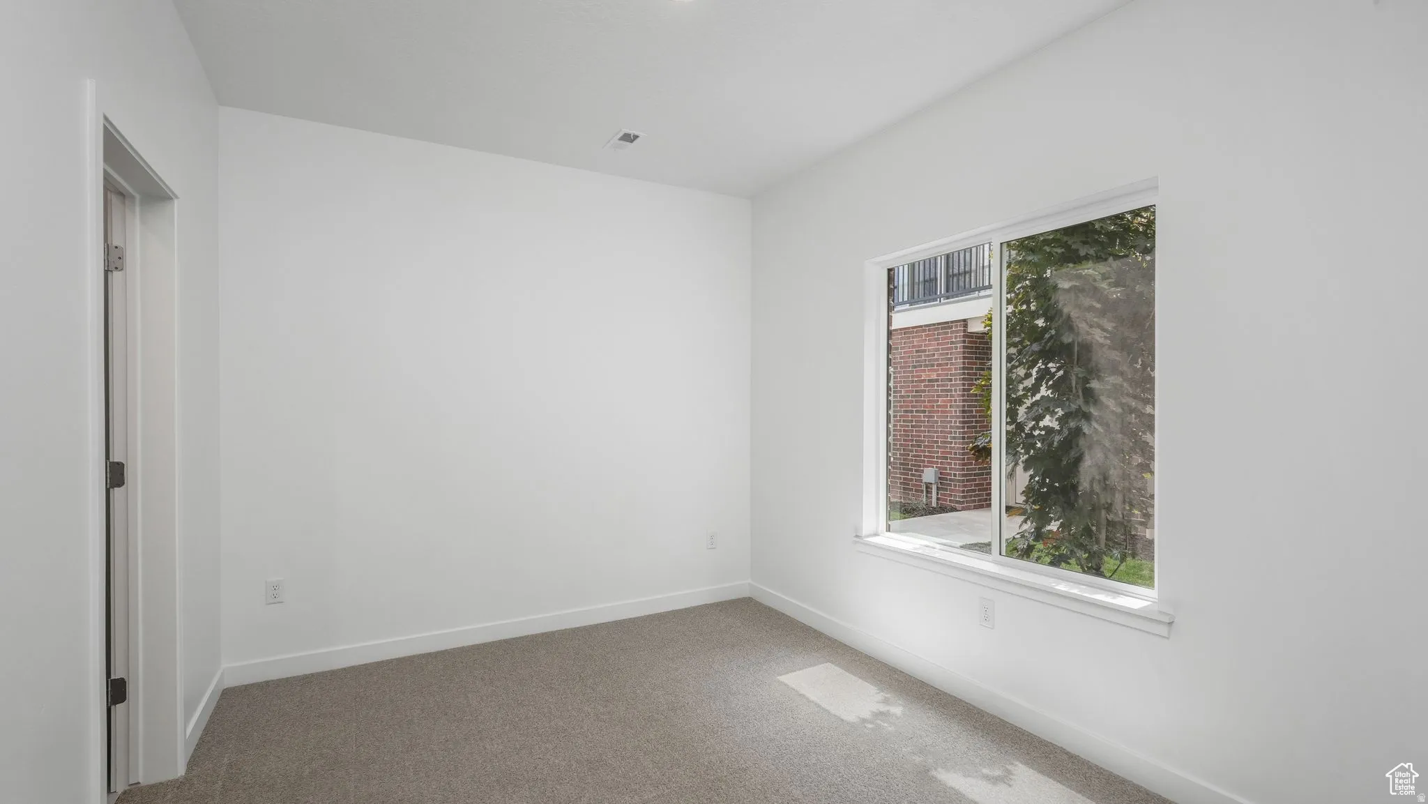 Carpeted room with a single window, recessed lighting, and a white interior door
