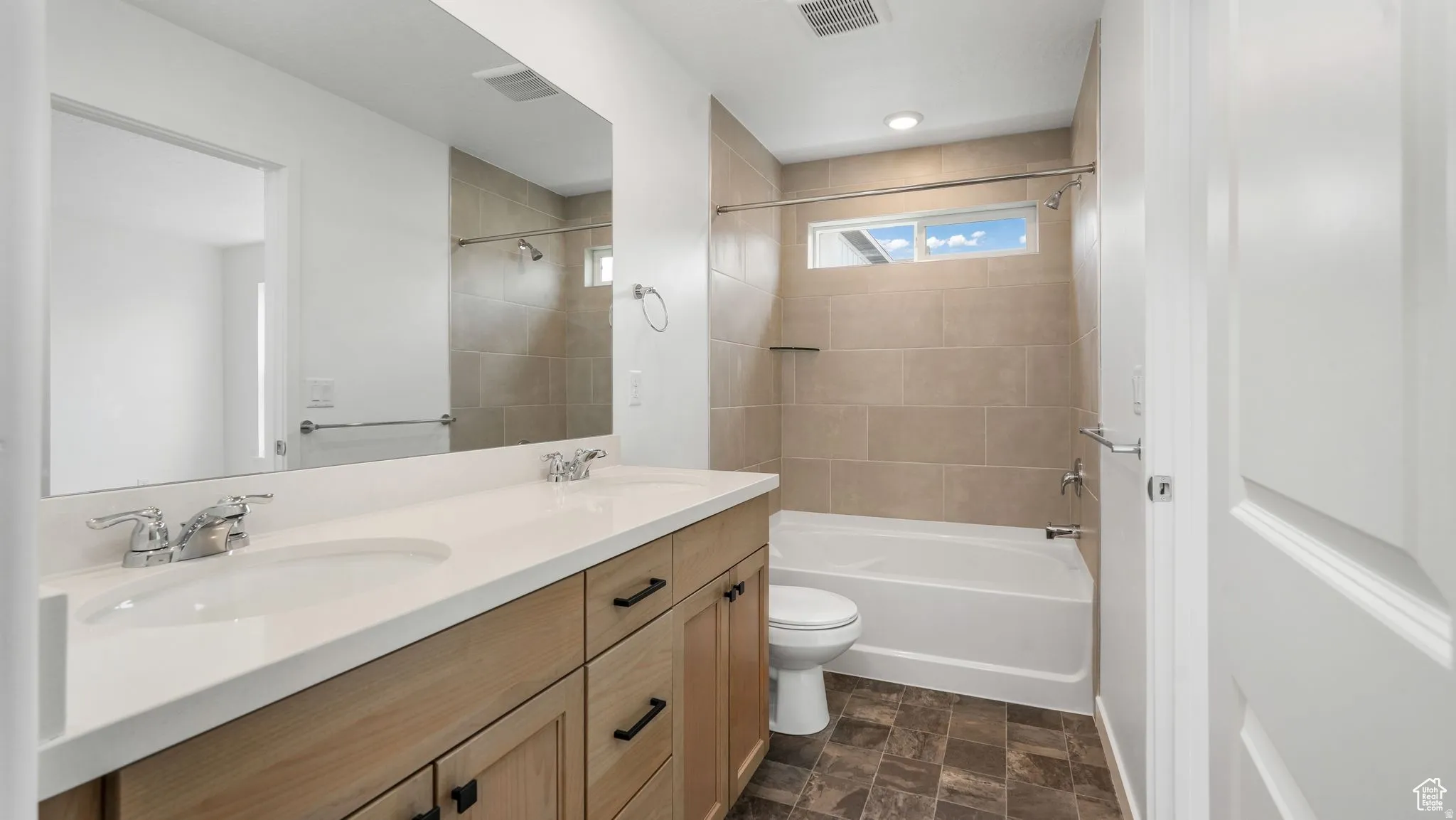Bathroom featuring a double vanity with light wood-finish cabinetry, white countertop, and rectangular undermount sinks