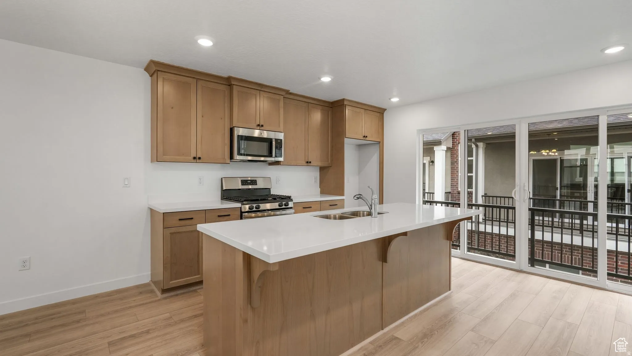 Modern kitchen featuring light wood-finish cabinetry, stainless steel appliances, and white countertops
