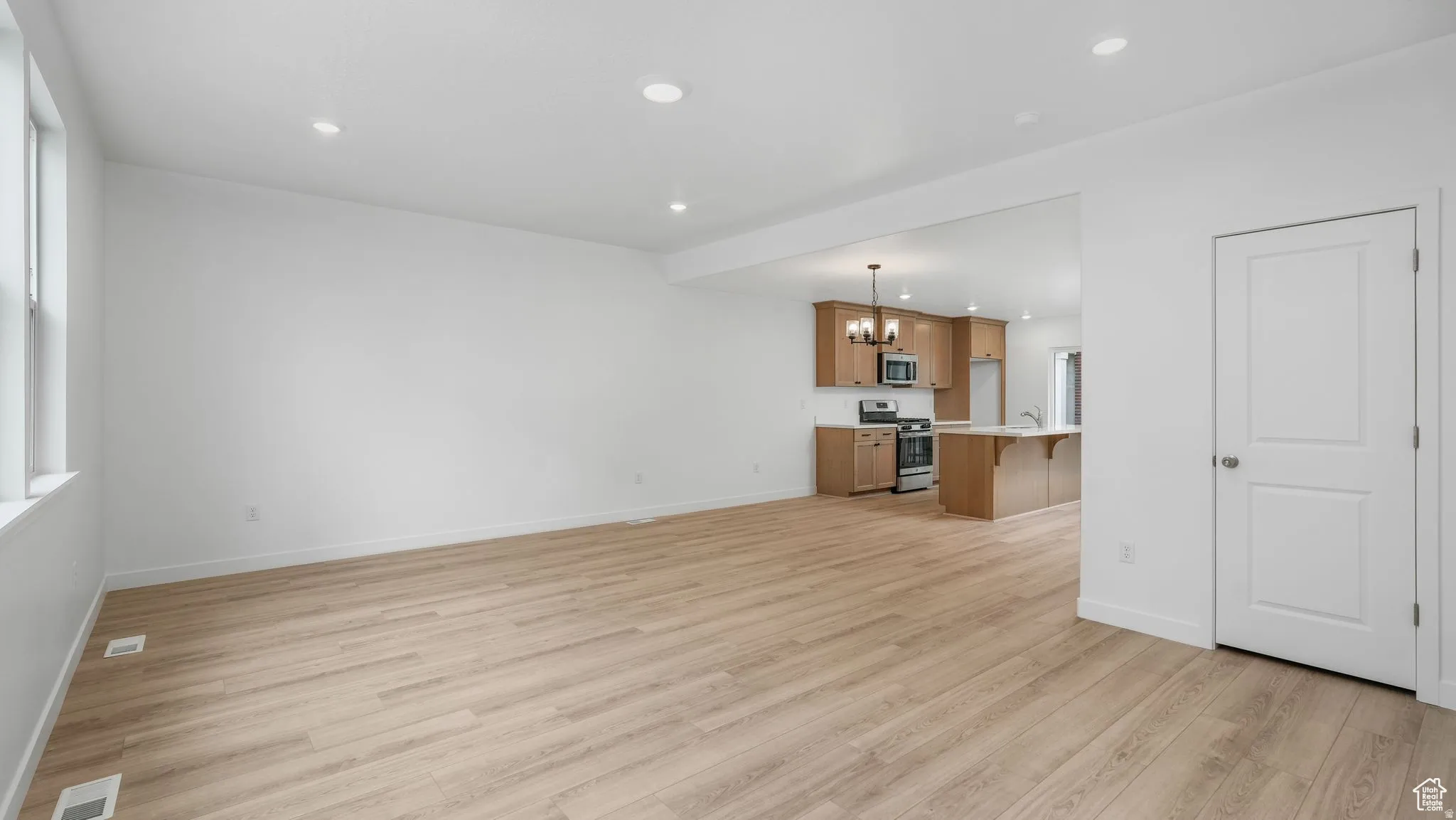 Spacious room featuring wood-finish flooring, recessed lighting, and white walls