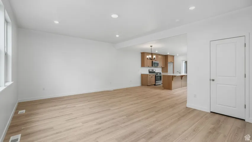 Spacious room featuring wood-finish flooring, recessed lighting, and white walls