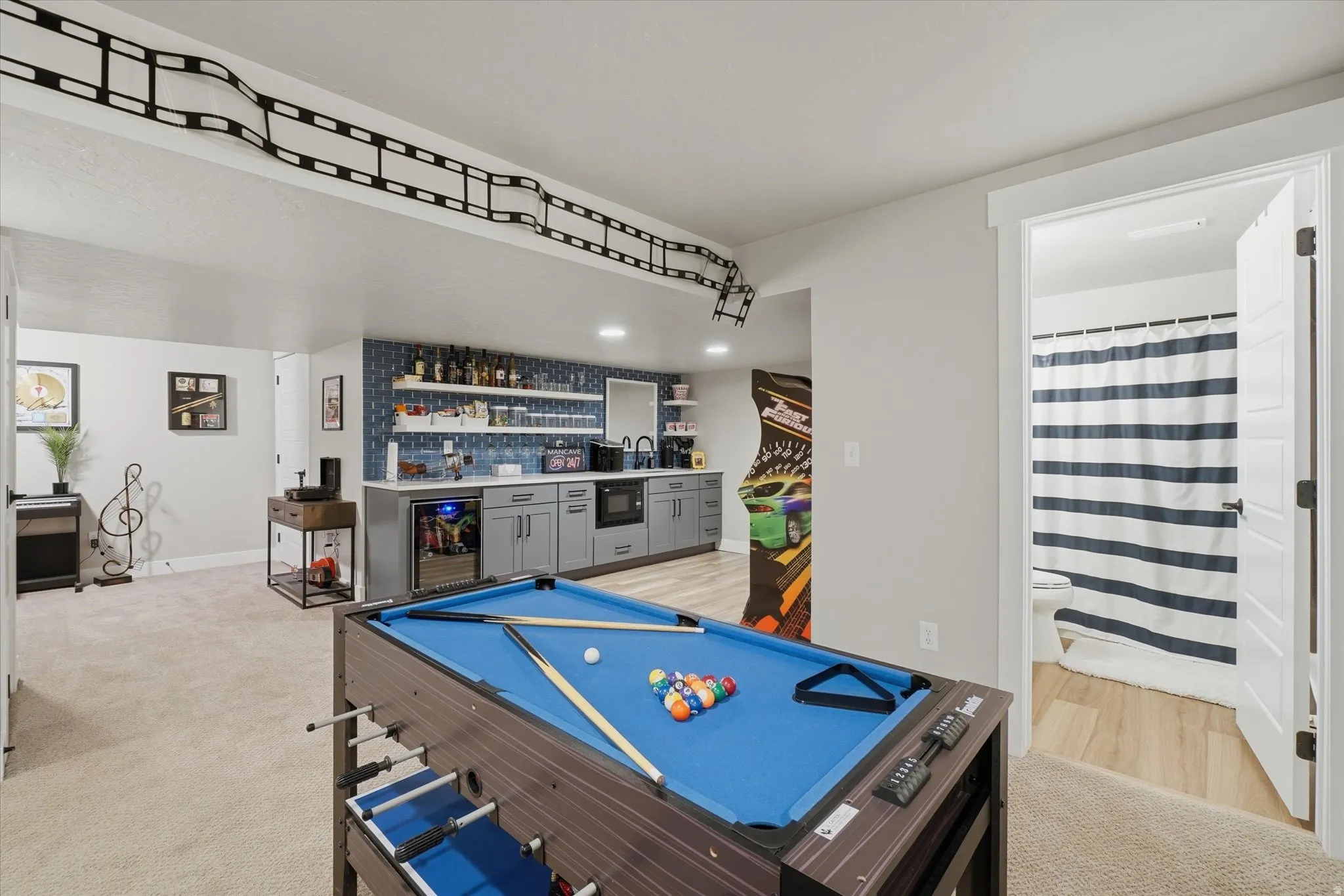 Recreation room featuring a built-in wet bar with gray cabinetry, a beverage refrigerator, and open shelving