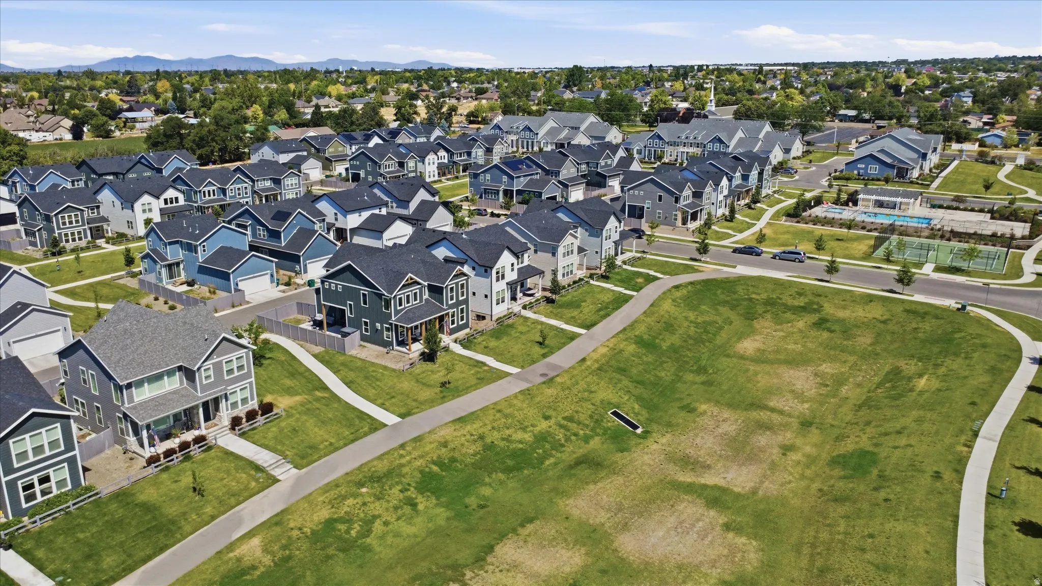 Residential development featuring a variety of home styles, green spaces, and a community pool
