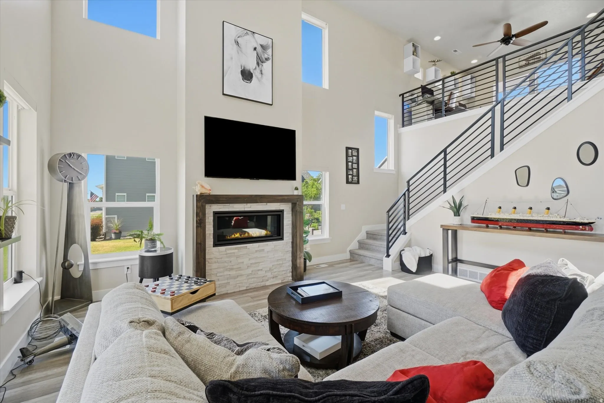 Open-concept living area featuring high ceilings, a fireplace with a stone surround, and light wood-finish flooring
