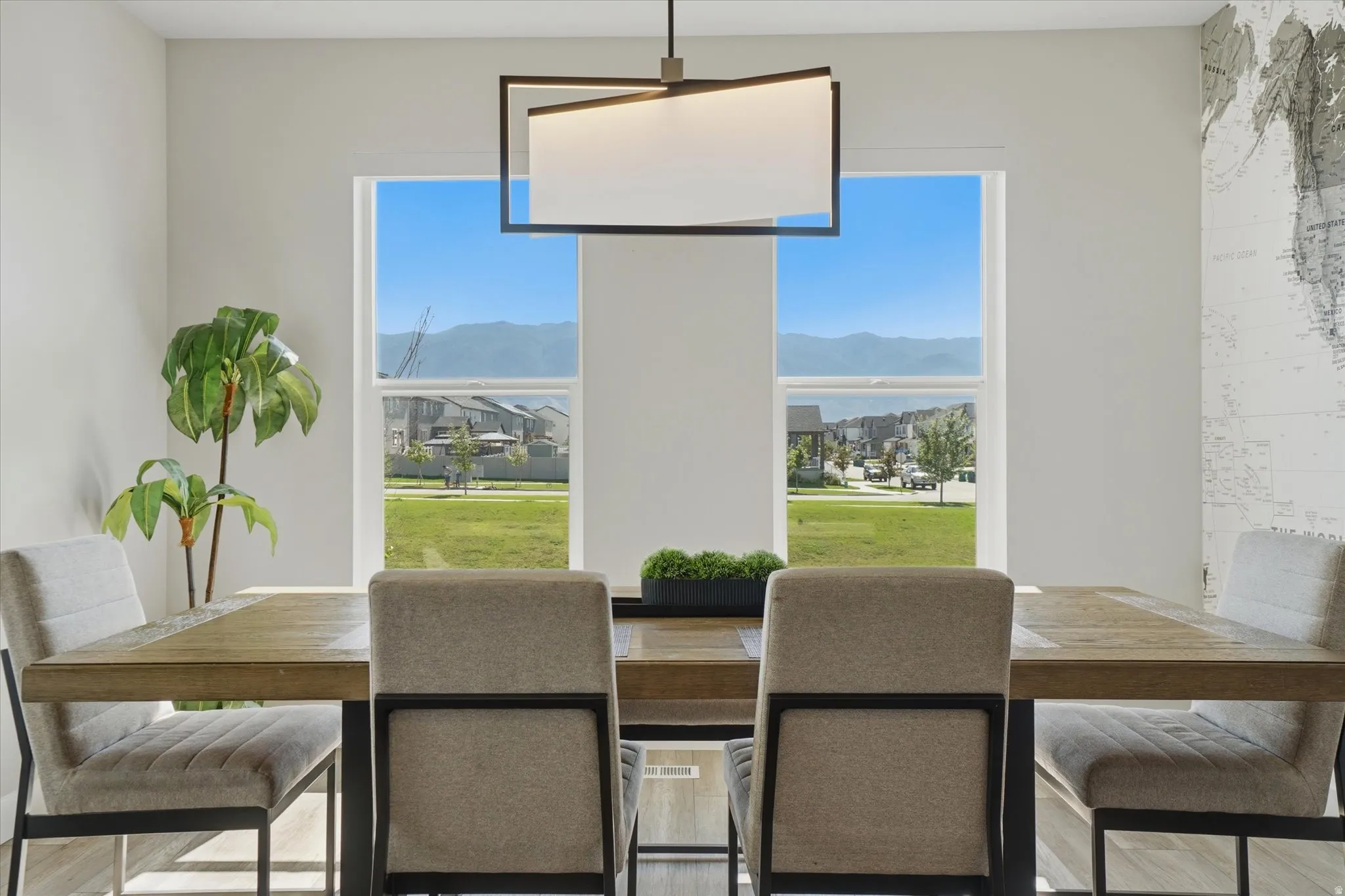 Dining area featuring a contemporary linear chandelier, wood-finish flooring, and expansive windows providing abundant natural light