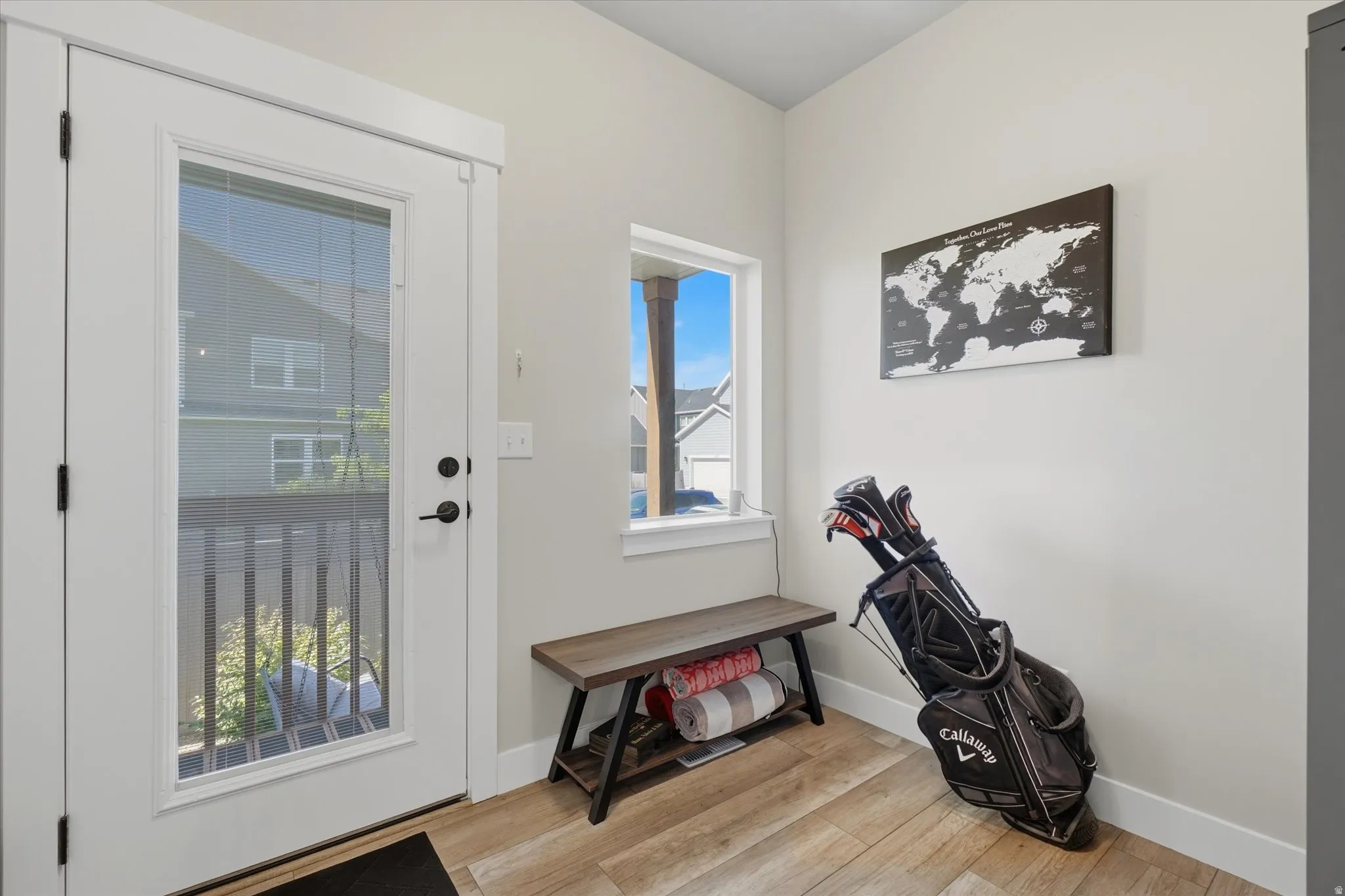 Entryway featuring a full-light glass door, wood-finish flooring, a single window, white trim, and light-toned walls