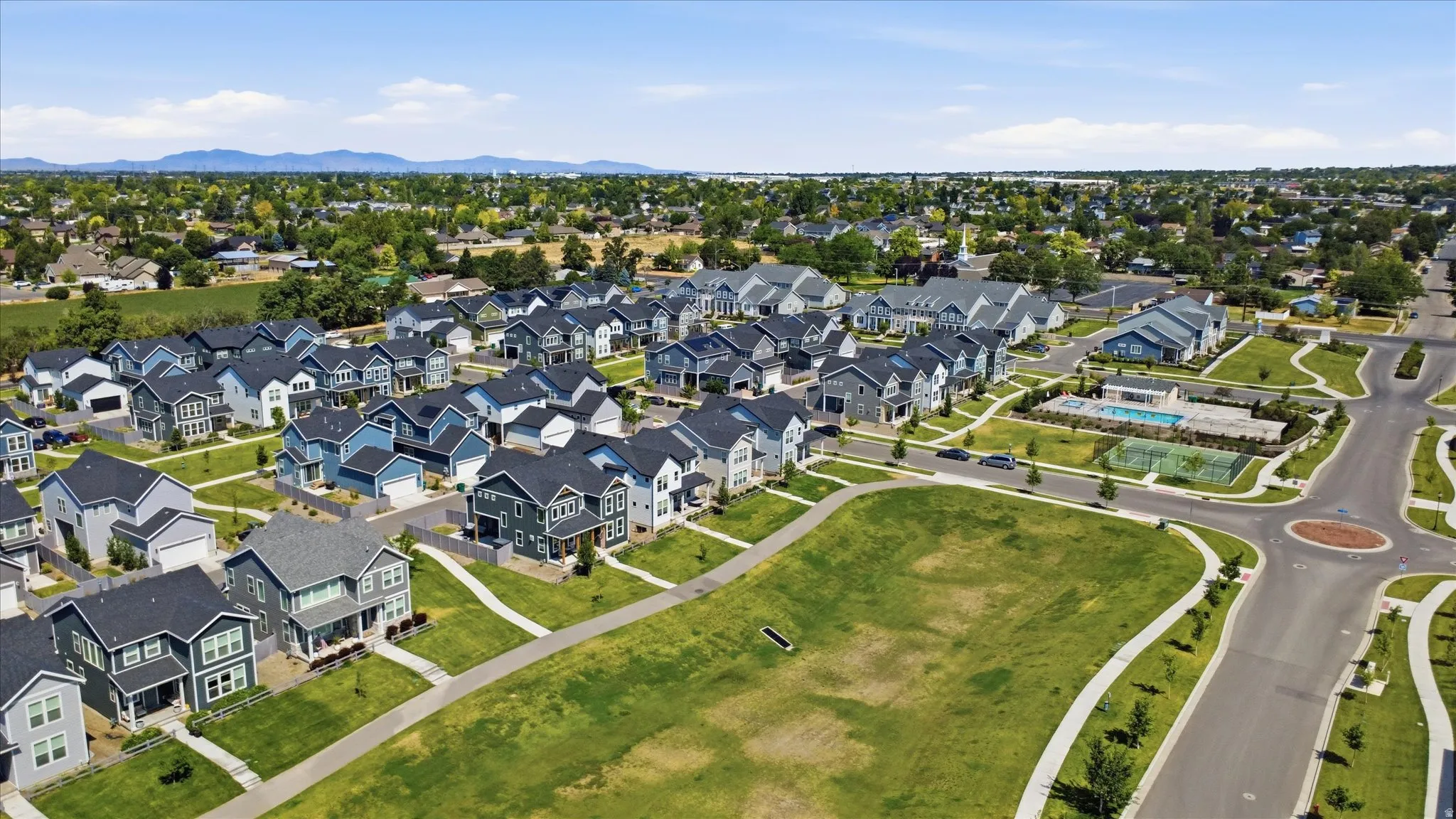 Expansive neighborhood featuring numerous detached residences, green spaces, and a community recreation area with a swimming pool and tennis courts
