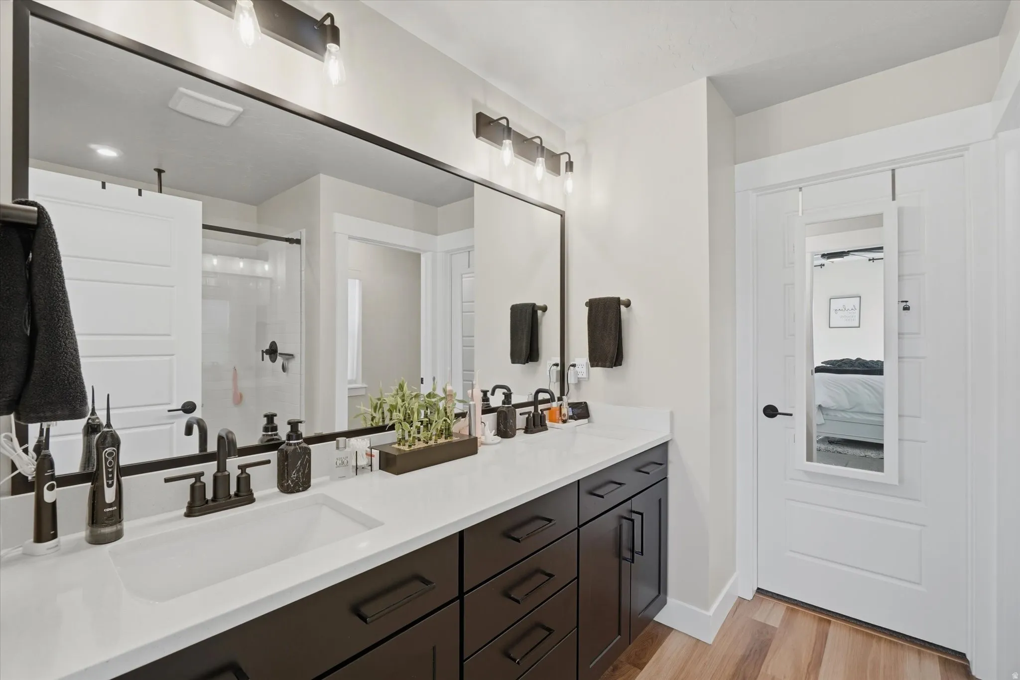 Double vanity with dark wood-finish cabinetry, white countertops, and matte black fixtures