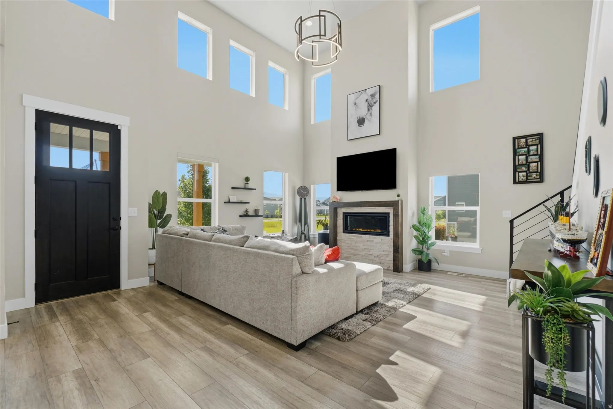 Two-story living area with wood-finish flooring, a contemporary fireplace with stone surround, and an open-tread staircase with horizontal railings