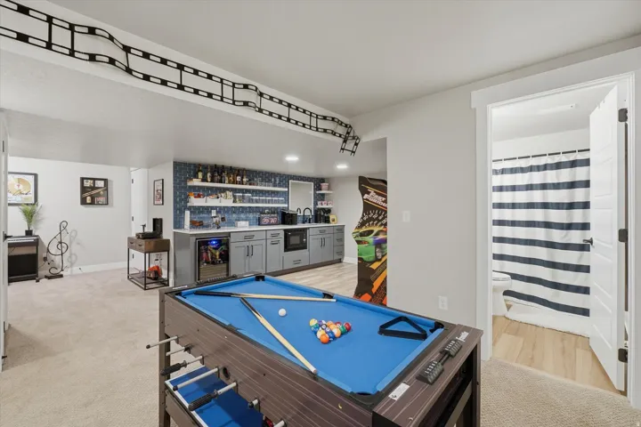 Recreation room featuring a built-in wet bar with gray cabinetry, a beverage refrigerator, and open shelving