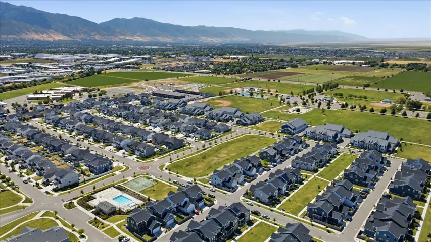 Aerial perspective of a developed residential community featuring single-family homes and multi-story buildings with dark roofs