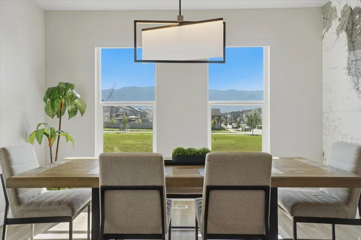 Dining area featuring a contemporary linear chandelier, wood-finish flooring, and expansive windows providing abundant natural light