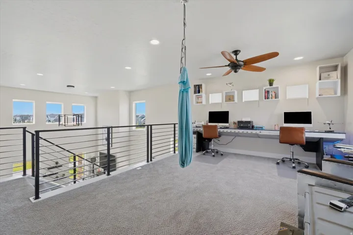 Expansive loft space featuring plush carpeting, recessed lighting, and a ceiling fan