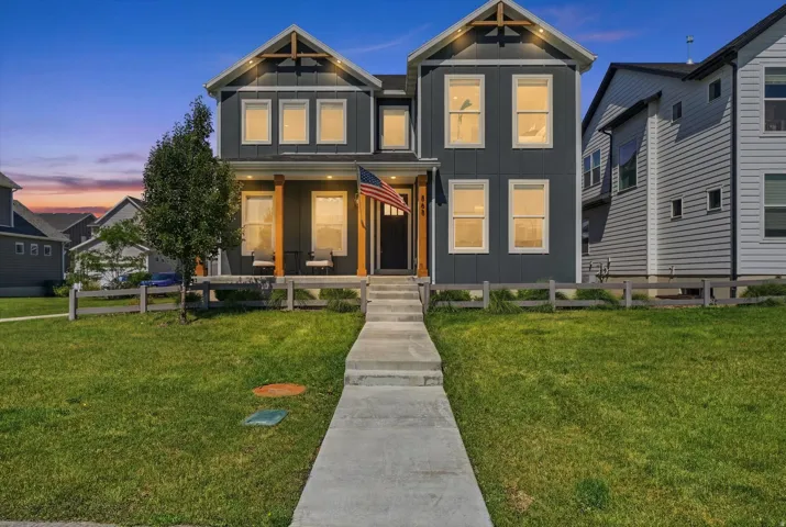 Modern two-story home featuring dark gray vertical siding, a covered porch with wood-clad pillars, and architectural gable accents