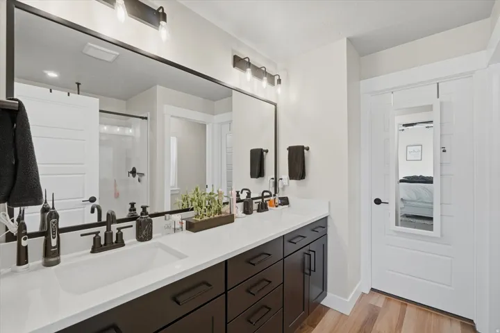 Double vanity with dark wood-finish cabinetry, white countertops, and matte black fixtures