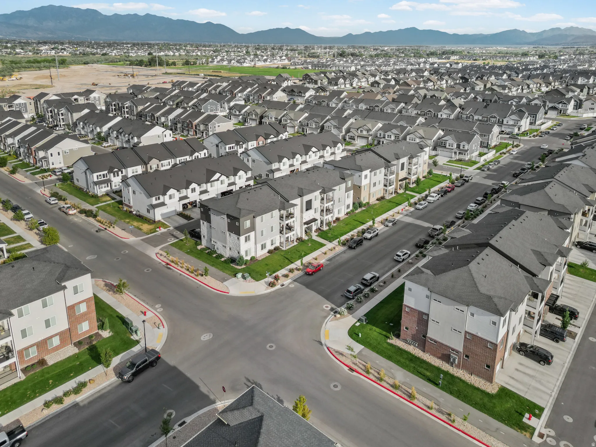 Aerial view of a residential community featuring a mix of multi-story townhomes and apartment buildings with dark gray roofs