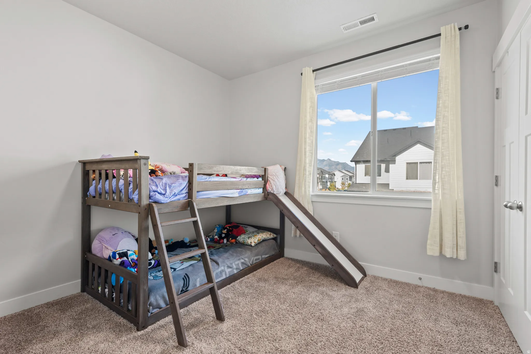 Carpeted room featuring a large window with white trim, a white paneled door, and neutral wall paint