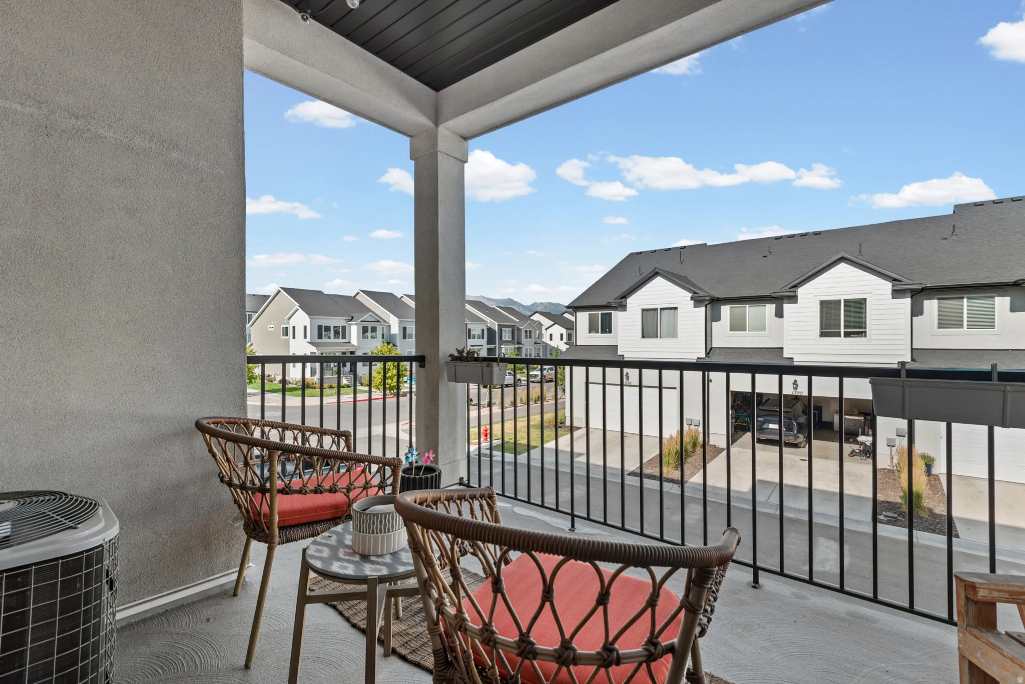Private balcony featuring concrete flooring, a black metal railing, and a textured stucco exterior wall