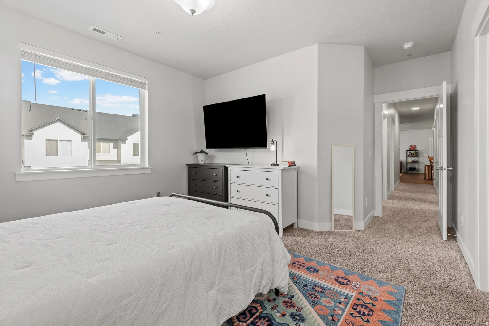Room featuring light neutral wall paint, carpet flooring, a large window with blinds, and white trim
