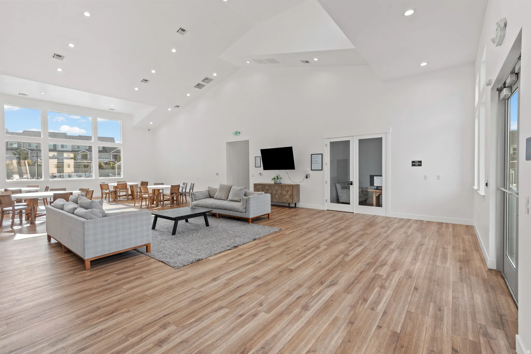 Expansive open-concept room featuring light wood-finish flooring and a high vaulted ceiling with recessed lighting