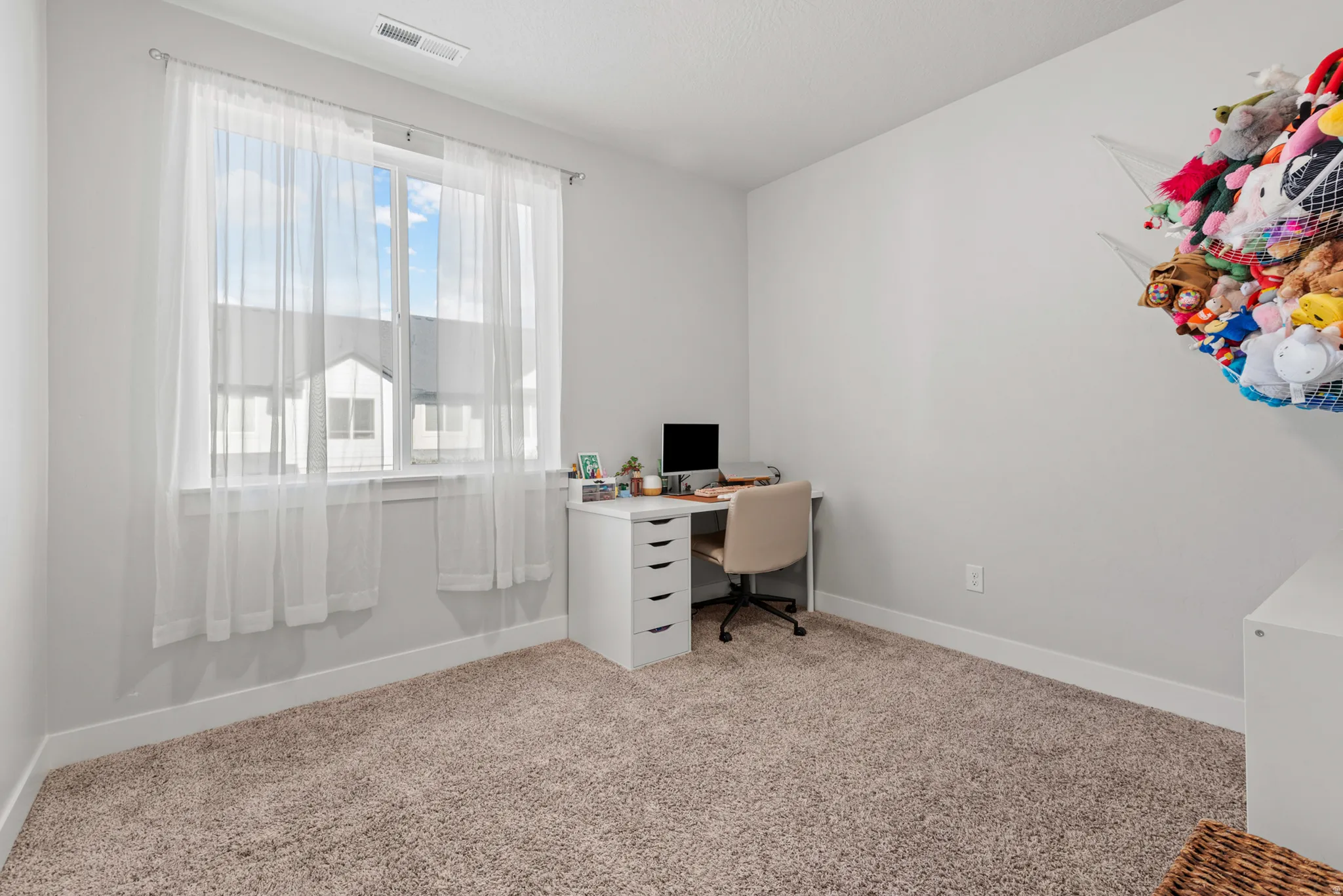 Neutral gray walls with white trim, featuring a large window with sheer white curtains