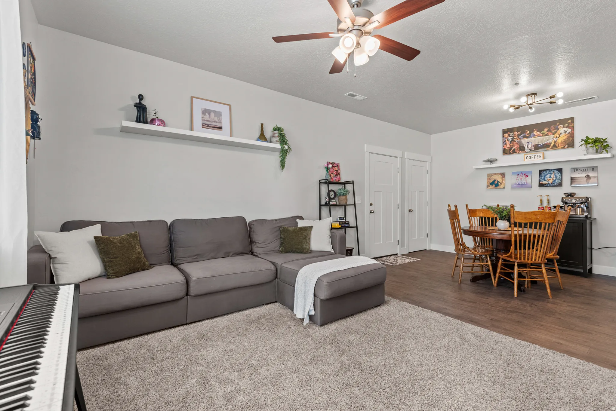 Open-concept living space featuring wood-finish flooring, a contemporary ceiling fan, and built-in floating wall shelves