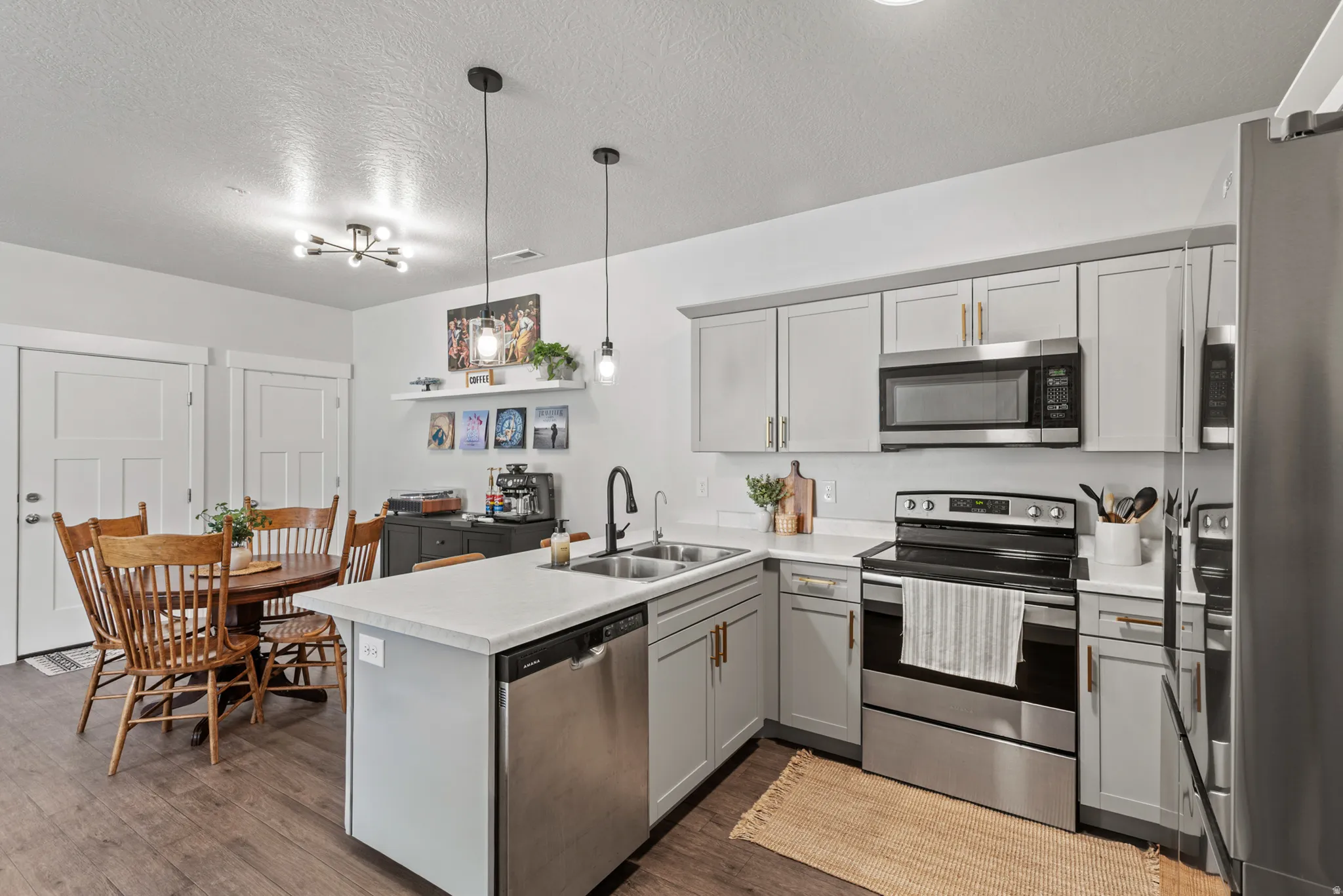 Modern kitchen featuring light gray cabinetry, stainless steel appliances, and a central island with a double sink