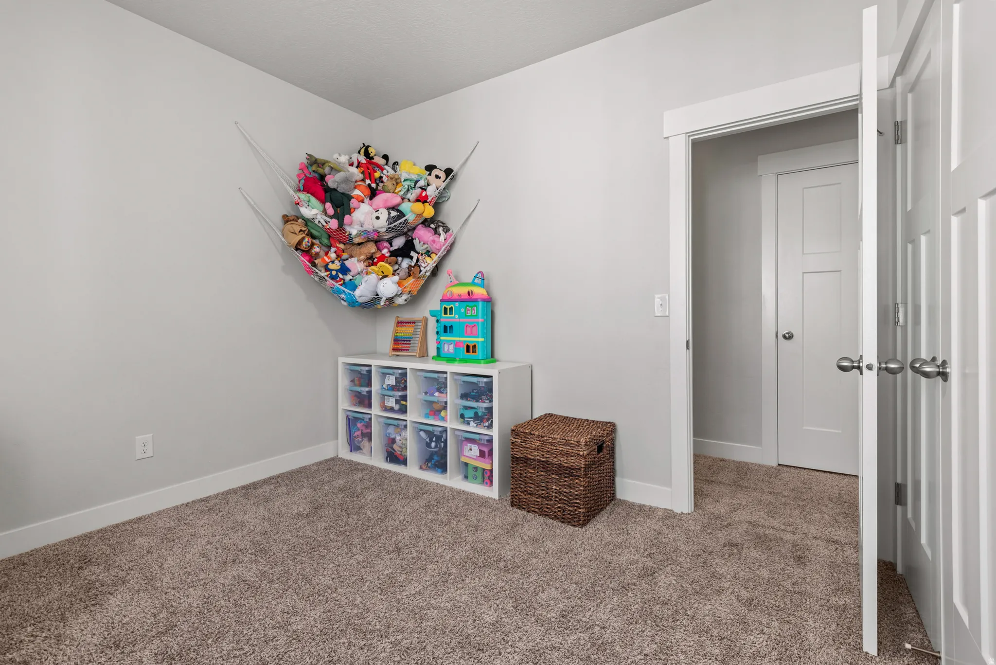 Neutral wall color with white trim, brown carpet flooring, and a white six-cube storage unit
