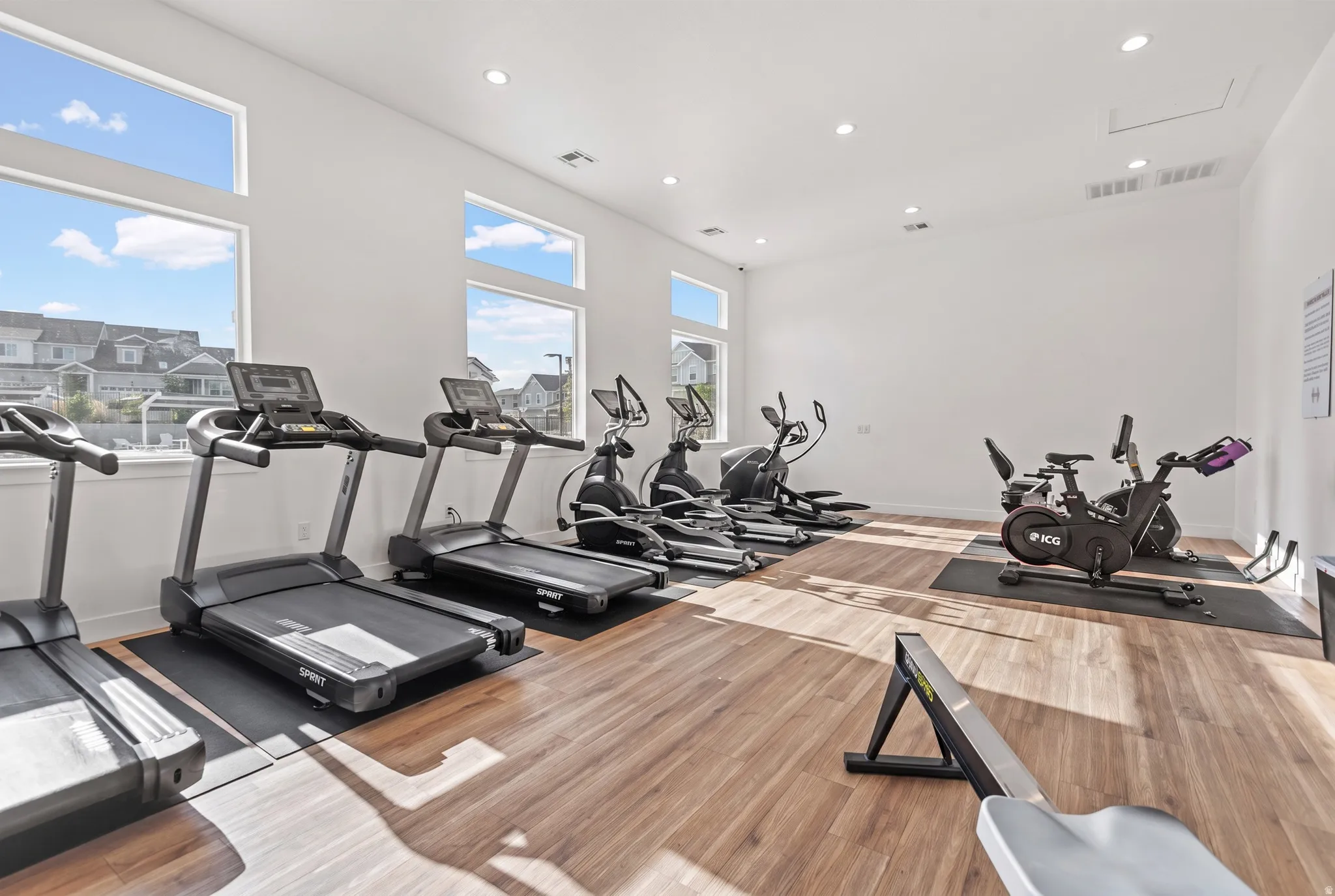 Fitness room featuring wood-finish flooring, recessed lighting, and large windows