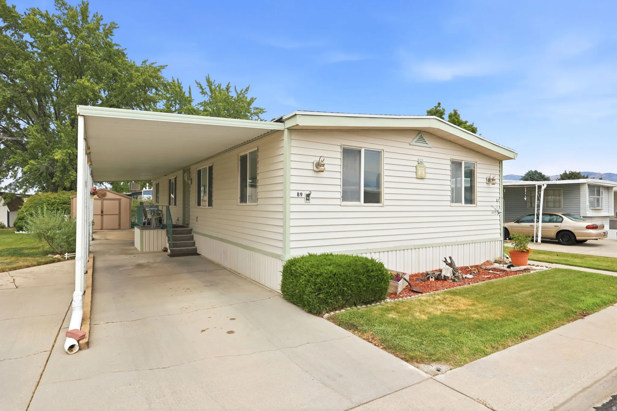 Exterior featuring light-toned horizontal siding, a covered carport, and a manicured lawn