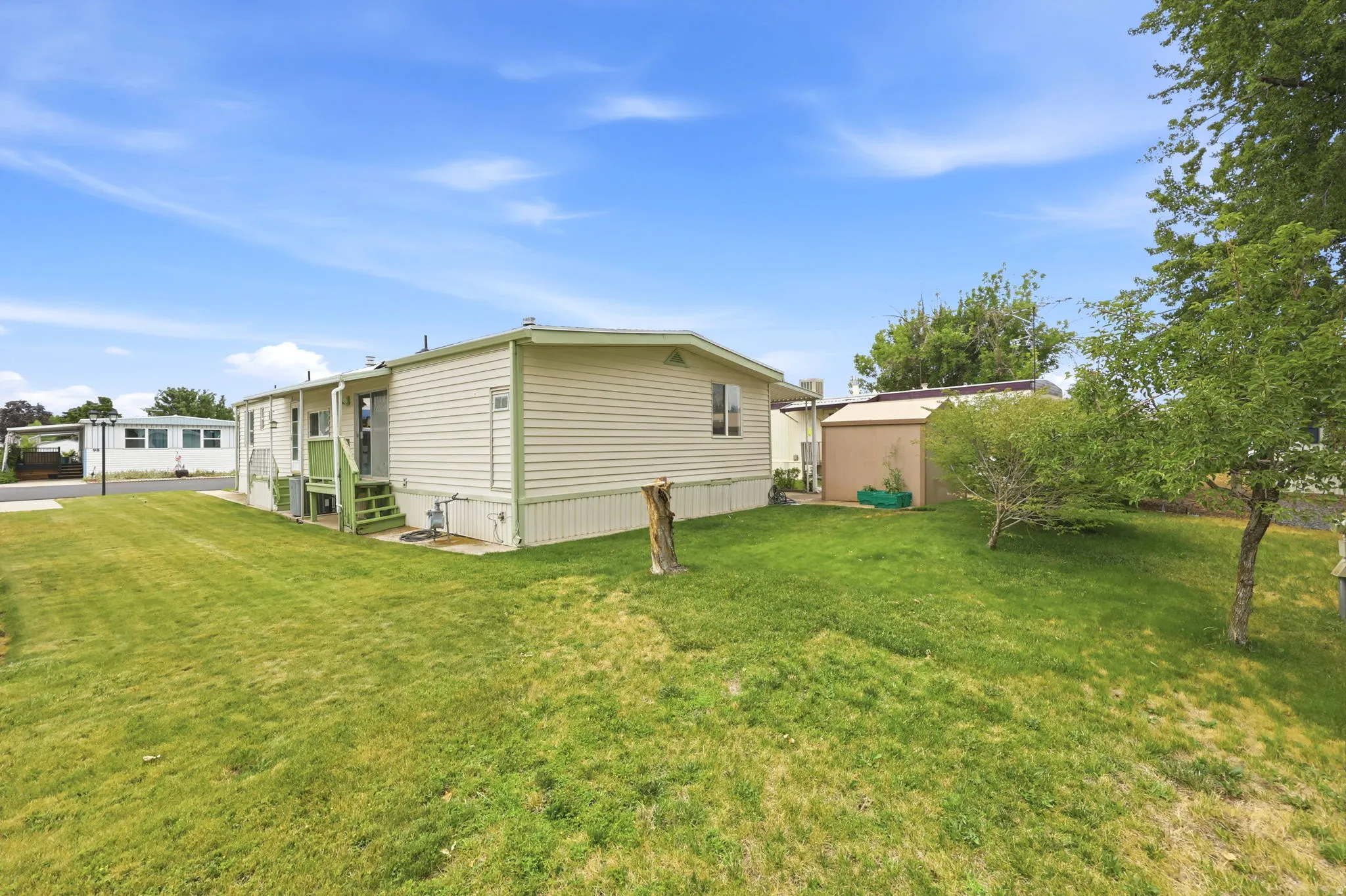 Expansive grassy yard with mature trees and a storage shed